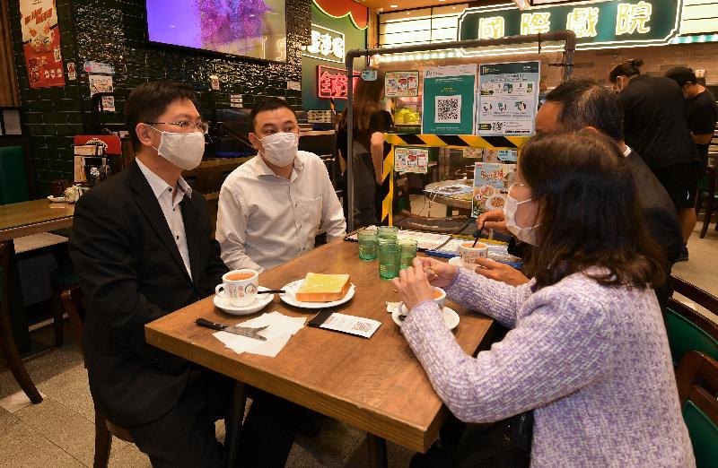 The Secretary for Innovation and Technology, Mr Alfred Sit (first left), chats with an owner of a local cafe kitchen during his visit to Kowloon City today (November 18) to learn more about the implementation of the "LeaveHomeSafe" mobile app. Looking on is the Deputy Director of the Food and Environmental Hygiene Department, Miss Diane Wong (first right).